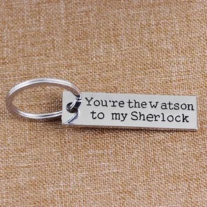 Sherlock and Watson silver alloy keychain with engraved quote on brown textured background