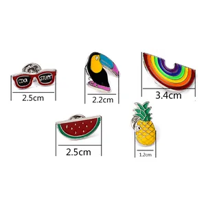 Détail de cinq broches en émail colorées incluant arc-en-ciel, toucan, ananas et pastèque