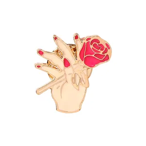 Detail einer Emaille-Brosche: Eine Hand hält eine rosa Rose mit goldenem Metallrand