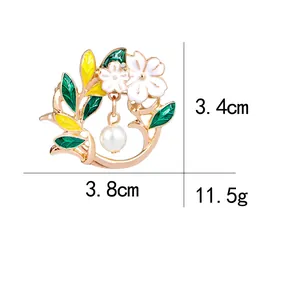 Elegant floral pin brooch with white enamel flowers, green leaves and a hanging pearl charm