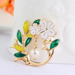 Floral brooch with green enamel leaves, white flowers and pearl drop in gold finish