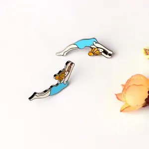 Detail of two diving girl enamel pins with blue swimsuits on a clean light background