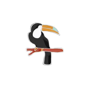Detailansicht einer Emaille-Tukan-Brosche mit lebhaftem tropischem Vogeldesign auf weißem Grund
