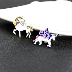 Detail of two cartoon unicorn enamel pins with rainbow wings and star patterns