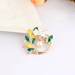 Detail of floral brooch with green enamel leaves, white flowers and pearl pendant