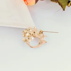 Close-up of golden hollow flower brooch with white pearl and secure safety pin back