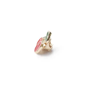 Macro detail of cherry enamel brooch with pink berries, green leaves and gold finish