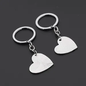 Pair of silver heart keychains with brushed and dotted textures on a dark background