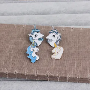 Detail of four colorful unicorn enamel pins on a gray velvet tray with golden edges