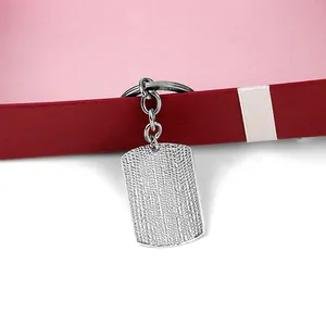 Detailed shot of silver textured rectangular keychain pendant displayed on a red gift box