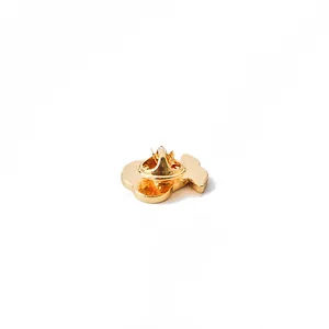 Macro shot of the polished gold metal back of a cherry brooch with butterfly clutch