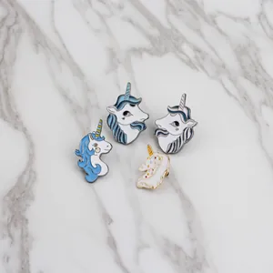 Set of four cute cartoon unicorn enamel pins in blue and white on marble background