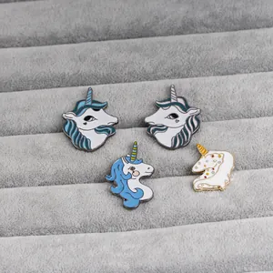 Detailed view of four colorful enamel unicorn brooches neatly arranged on a gray velvet tray