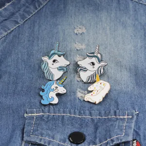 Set of four unicorn enamel pins styled on a dark blue denim shirt pocket background