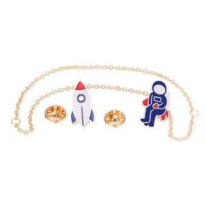 Détail du lot de broches émaillées astronaute et fusée avec chaîne dorée reliée