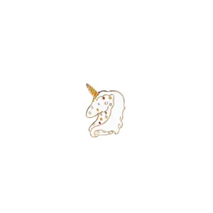 Close-up of a white enamel unicorn brooch with colorful dots and golden spiral horn detail