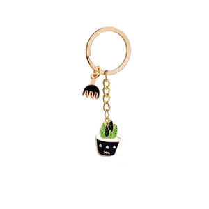 Detail of gold keychain with enamel pendants featuring a green cactus and a garden rake