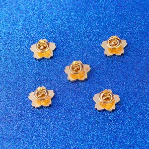 Vue macro de cinq badges fleurs de cerisier dorés avec fermoirs papillon sécurisés