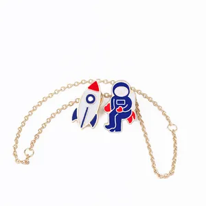 Détail d'un bracelet doré avec des breloques émaillées de fusée et d'astronaute