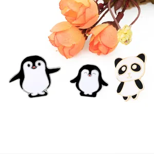 Detailed view of three enamel pins featuring cartoon panda and penguins with gold metal edges