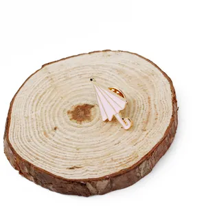 Vue détaillée d'une broche parapluie en émail rose et doré sur un fond en bois rustique