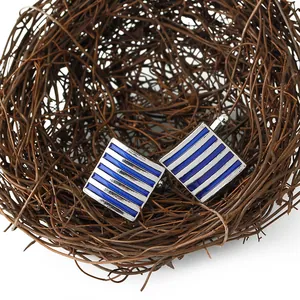 Close-up of square men's cufflinks with blue and silver stripes in a decorative nest