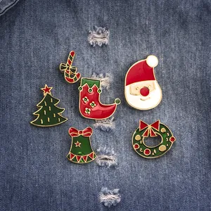 Set di spille natalizie in smalto con Babbo Natale e albero su sfondo in denim