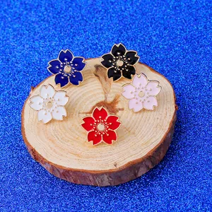 Lot de cinq broches en émail en forme de cerisier sur une tranche de bois rustique