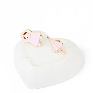 Détail de broches en émail rose petite fille en imperméable et parapluie sur plateau