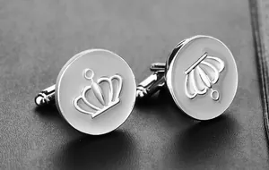 Macro view of silver round crown cufflinks on black textured leather background