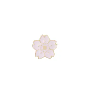 Détail d'une broche en émail fleur de cerisier rose avec des bords en métal doré