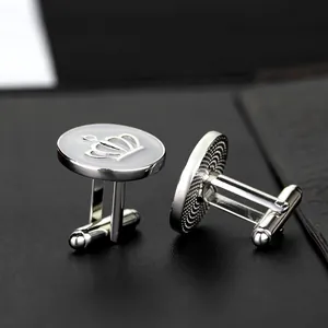 Macro view of silver crown cufflinks with white enamel on professional black leather surface