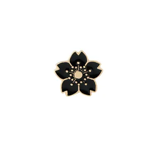 Détail d'une broche fleur de cerisier en émail noir avec bords et centre dorés polis