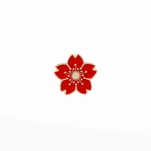 Détail d'une broche en émail fleur de cerisier rouge avec bordure dorée