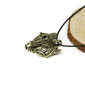 Macro detail of bronze wolf head pendant with black rhinestones on rustic wood background