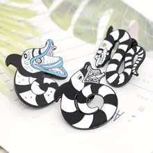 Close-up of three Beetlejuice Sandworm enamel pins with black and white stripes on paper