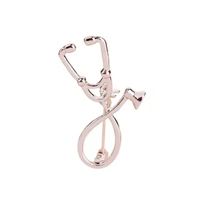 Detailed close-up of a rose gold stethoscope brooch with polished metal finish and clasp