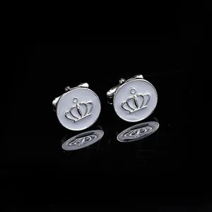 Silver crown cufflinks for men with white enamel inlay on reflective black background