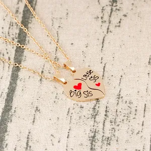 Golden Big Sis and Little Sis heart split pendant necklaces on textured background