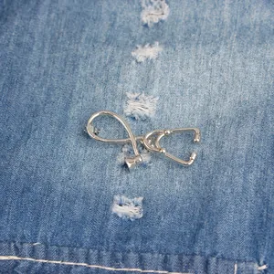 Polished silver stethoscope brooch pin for medical professionals on blue denim fabric