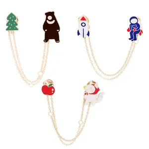 Detail of enamel lapel pins with gold chain featuring rocket and astronaut space theme