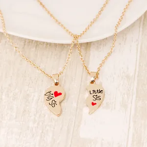 Golden Big Sis Little Sis heart pendant necklaces set on elegant wooden background