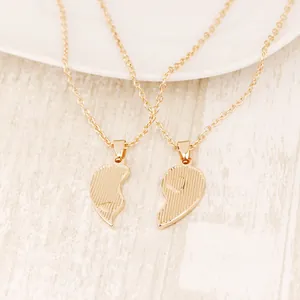 Detailed view of Big Sis and Little Sis golden heart puzzle pendants on a wood surface