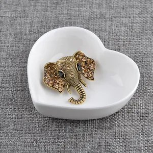 Detailed macro of vintage elephant head brooch with amber rhinestones on a white plate