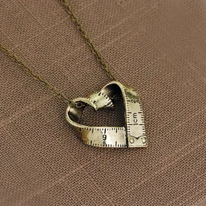Gros plan d'un pendentif cœur vintage en bronze style mètre ruban avec gravures précises