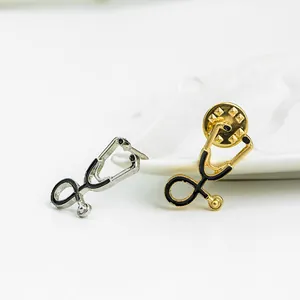 Détail macro de broches stéthoscope en or et argent avec émail noir et fermoir papillon