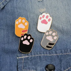 Set of four cute cartoon cat paw enamel pins in various colors on denim fabric