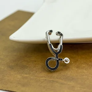 Broche stéthoscope vintage argentée avec émail noir sur une assiette en céramique