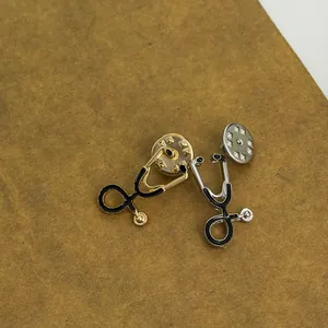 Détail des broches stéthoscope en or et argent avec émail noir et fermoirs métalliques