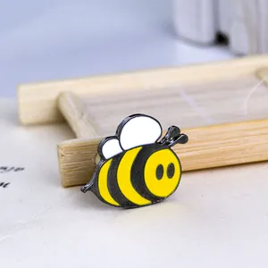 Close-up of a cartoon bee enamel brooch with yellow and black wings on a bamboo tray
